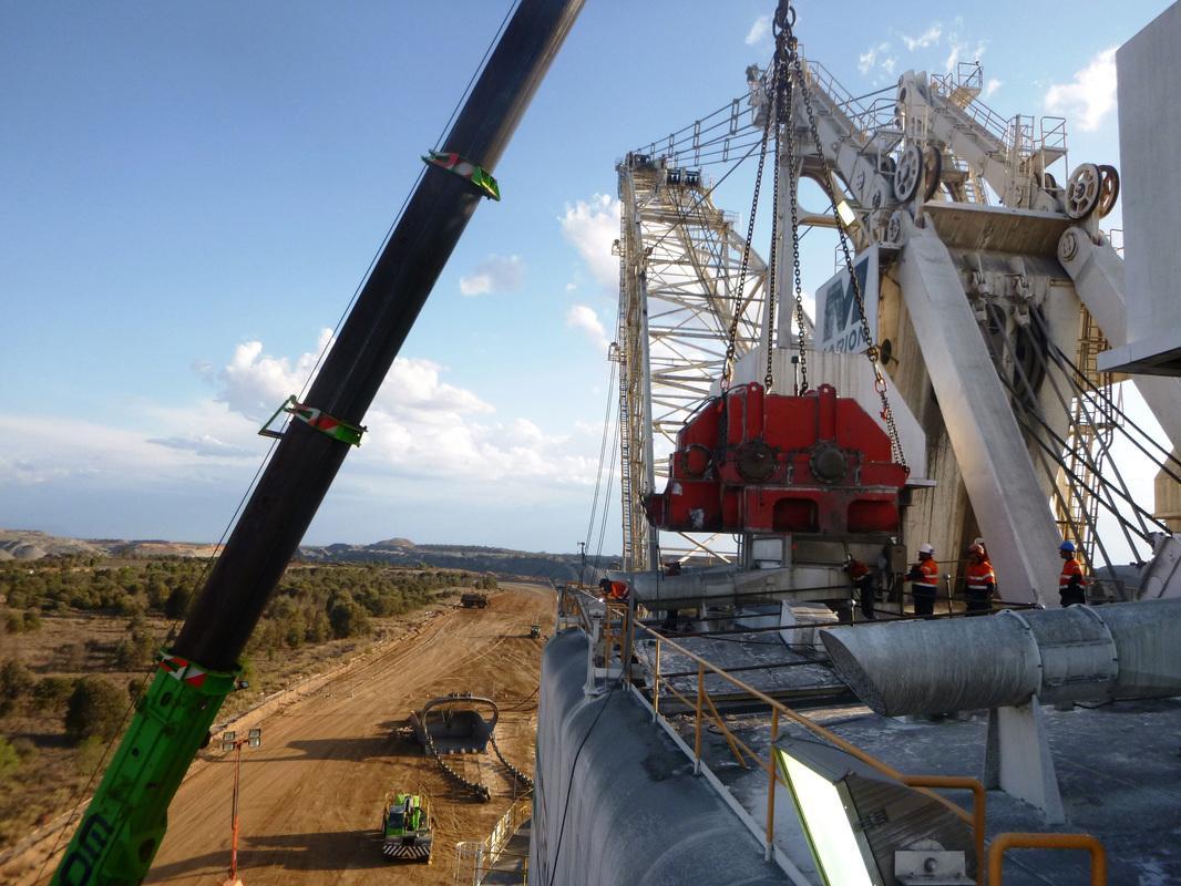 Crane hoisting the red Marion 8750 dragline propel gear case during an on-site change-out, ABC crew on the platform