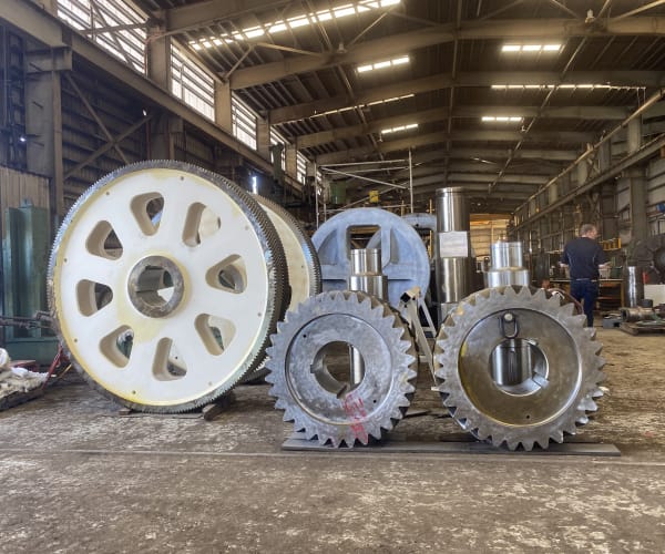 Three large fabricated gears of varying sizes standing upright on the workshop floor, showing the scale of the work