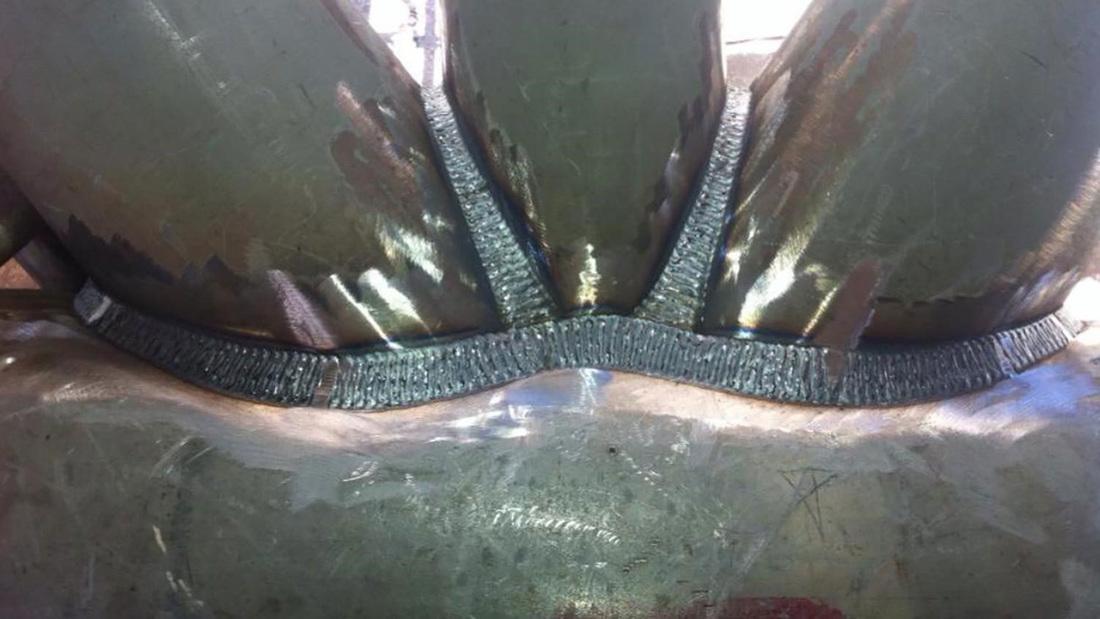 Close-up of a multi-pass structural weld seam running along the joint of a large fabricated steel component