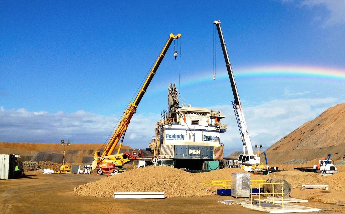Two mobile cranes rigged over a Peabody P&H face shovel during a field rebuild, rainbow behind