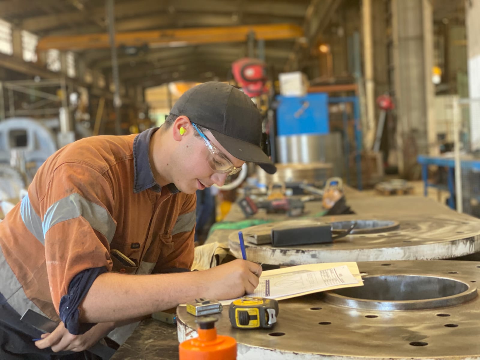 ABC Heavy Engineering apprentice in hi-vis marking out and measuring a large machined flange in the workshop